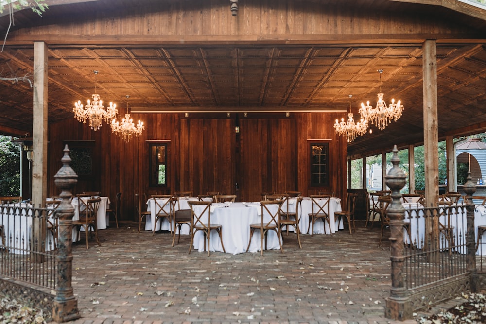 an outdoor dining area with tables and chandeliers