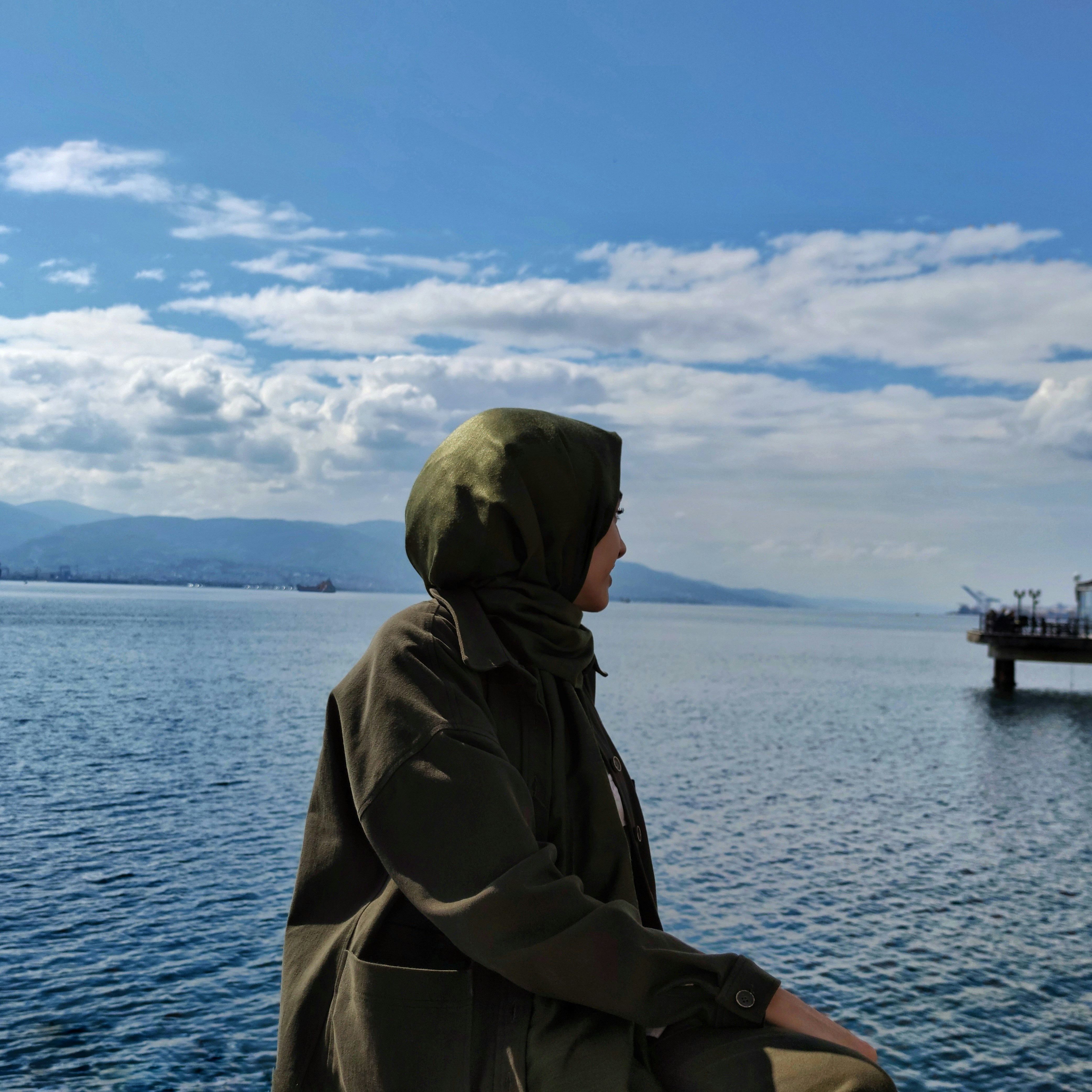A woman sitting on a boat looking out at the water photo – Free Apparel ...