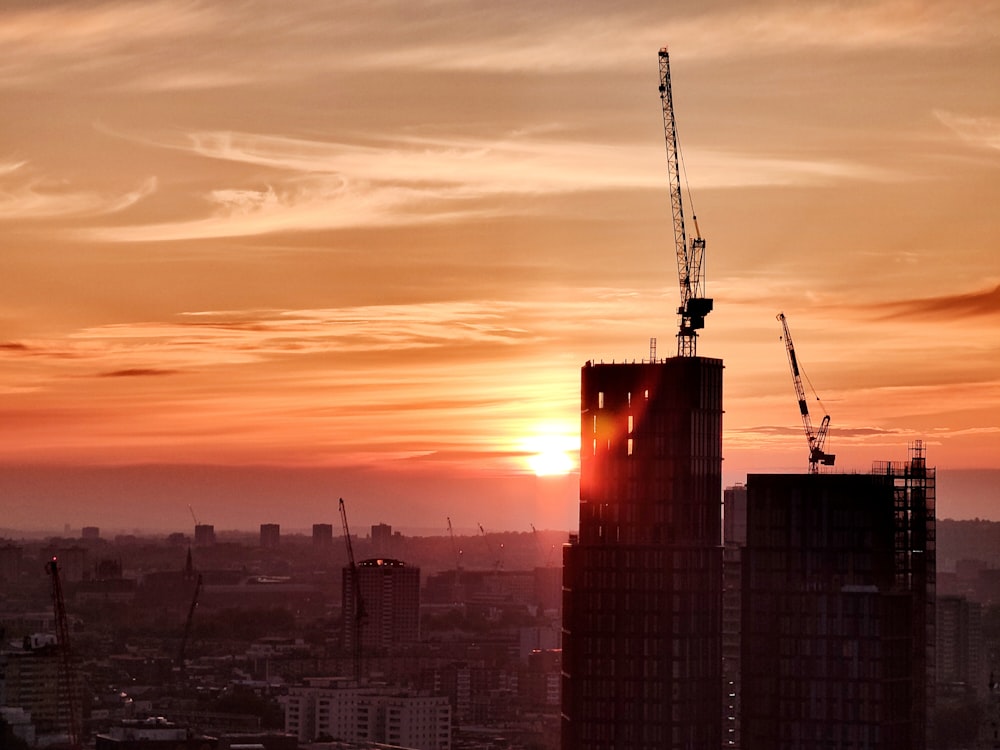 the sun is setting over a city with tall buildings