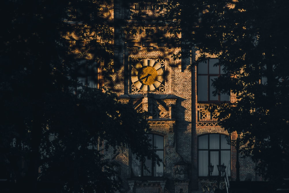 a clock on the side of a building with trees in front of it