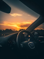 Audi luxury car cruising along a scenic highway at sunset, showcasing comfort and style.