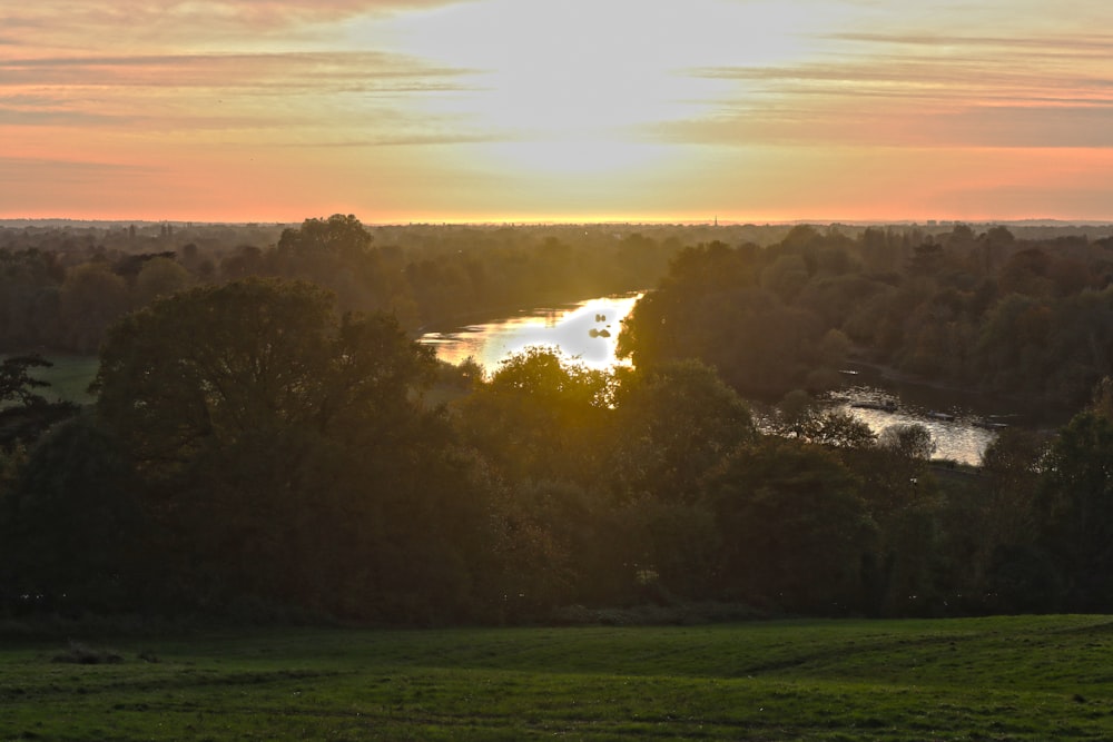 the sun is setting over a river in the distance