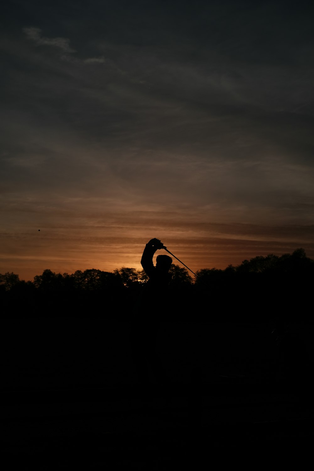 a silhouette of a person holding a golf club