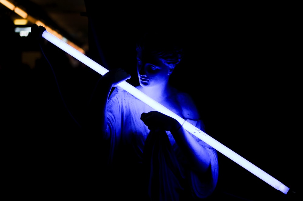 a man holding a light saber in the dark