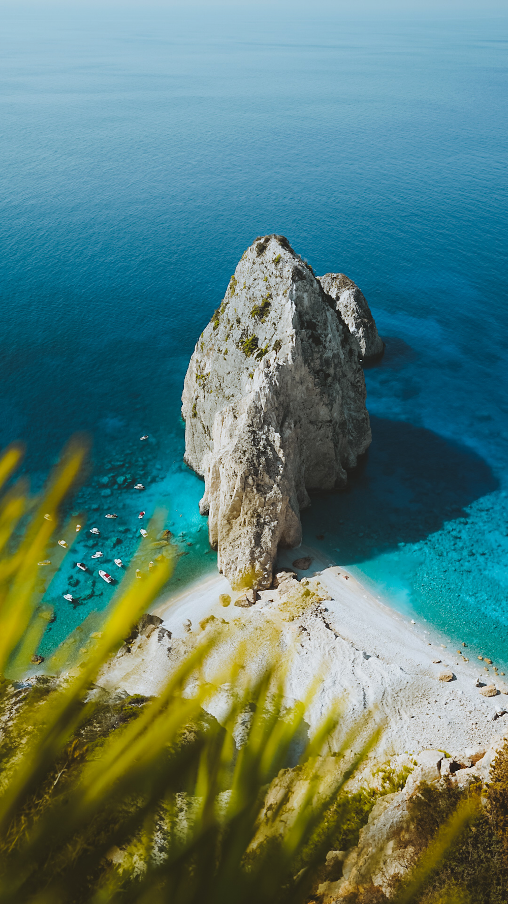 Una grande roccia seduta sulla cima di una spiaggia vicino all'oceano