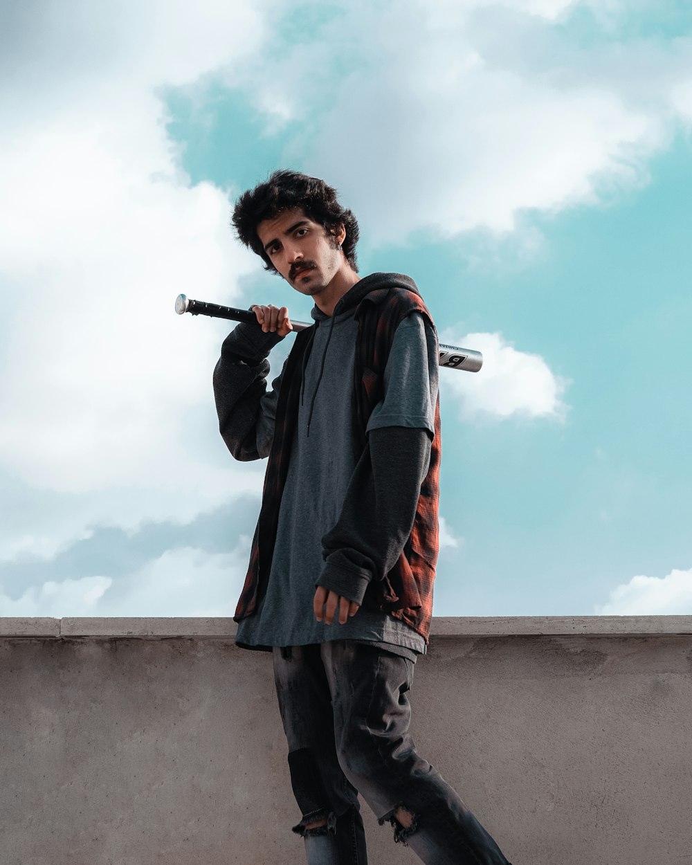 a man standing on a ledge holding a baseball bat