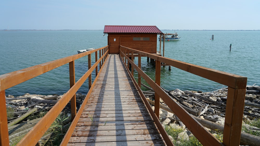a wooden walkway leading to a small house on the water