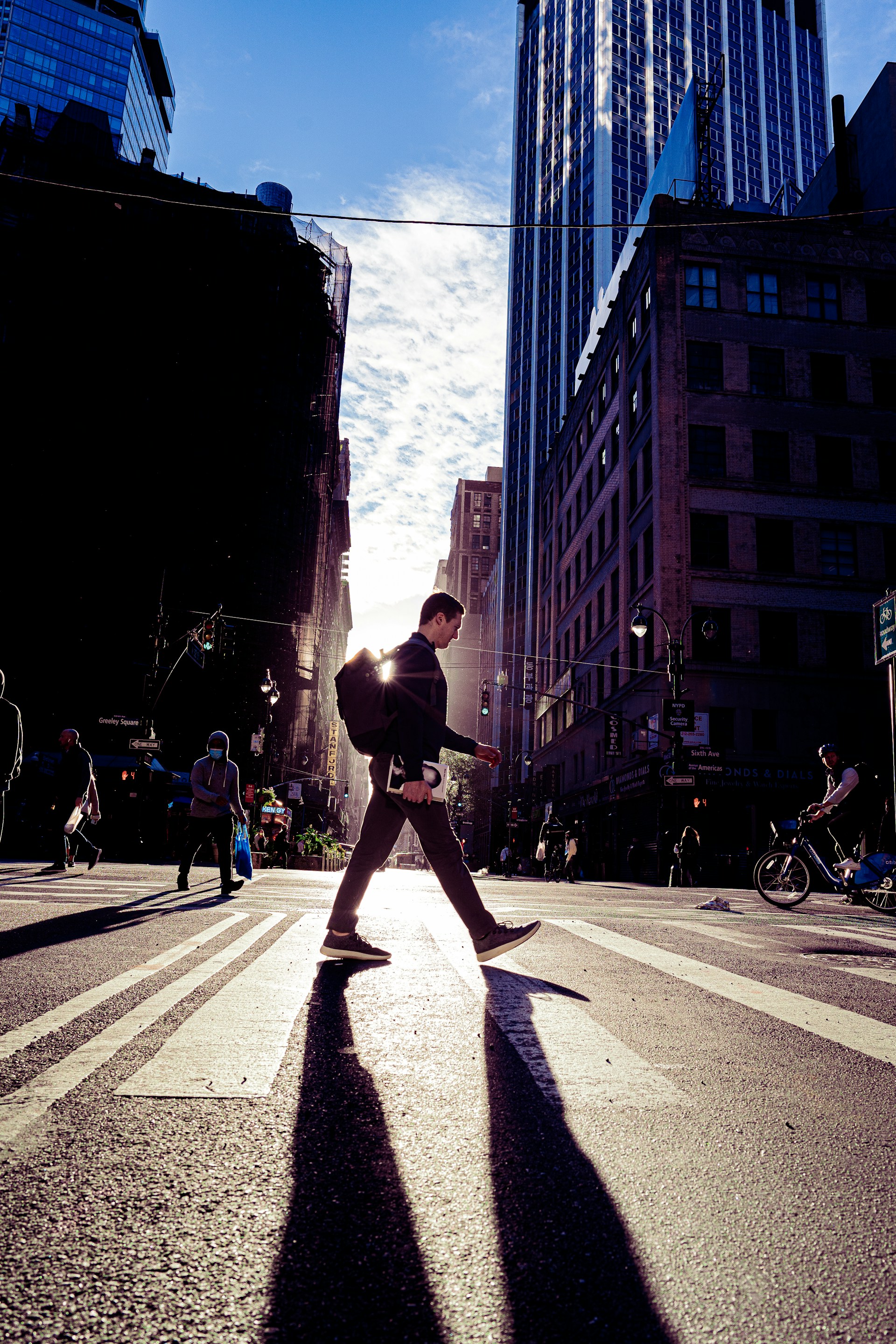 a man walking across a street next to tall buildings