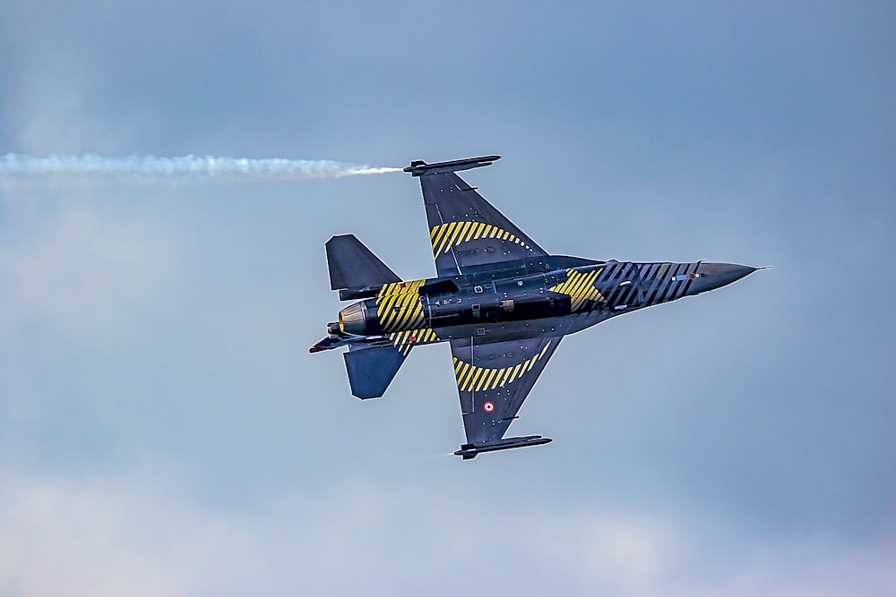 a fighter jet flying through a cloudy blue sky