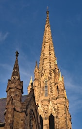 Drone inspecting a tall church steeple on a clear day.