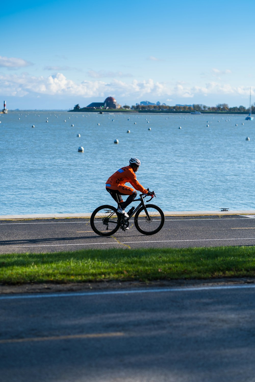 a man riding a bike down a road next to a body of water
