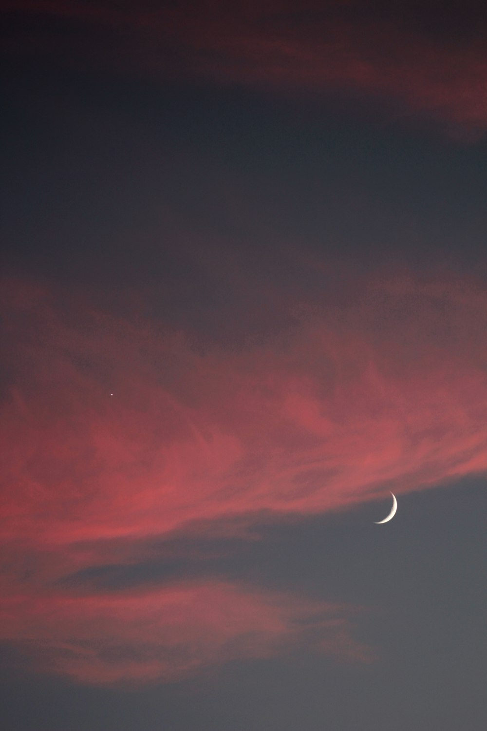 a red sky with a half moon in the distance