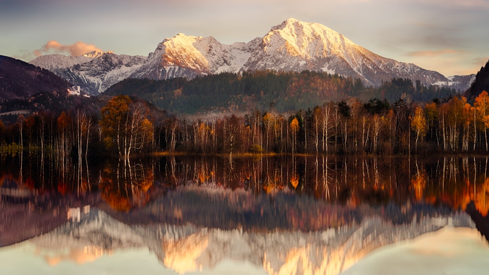 a mountain range is reflected in the still water of a lake