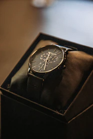 Close-up of a luxury wristwatch with a black dial and gold details resting on a black velvet cushion