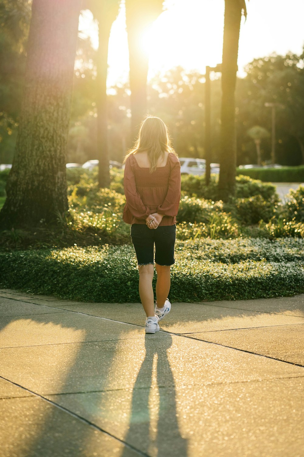 a woman walking down a sidewalk in a park