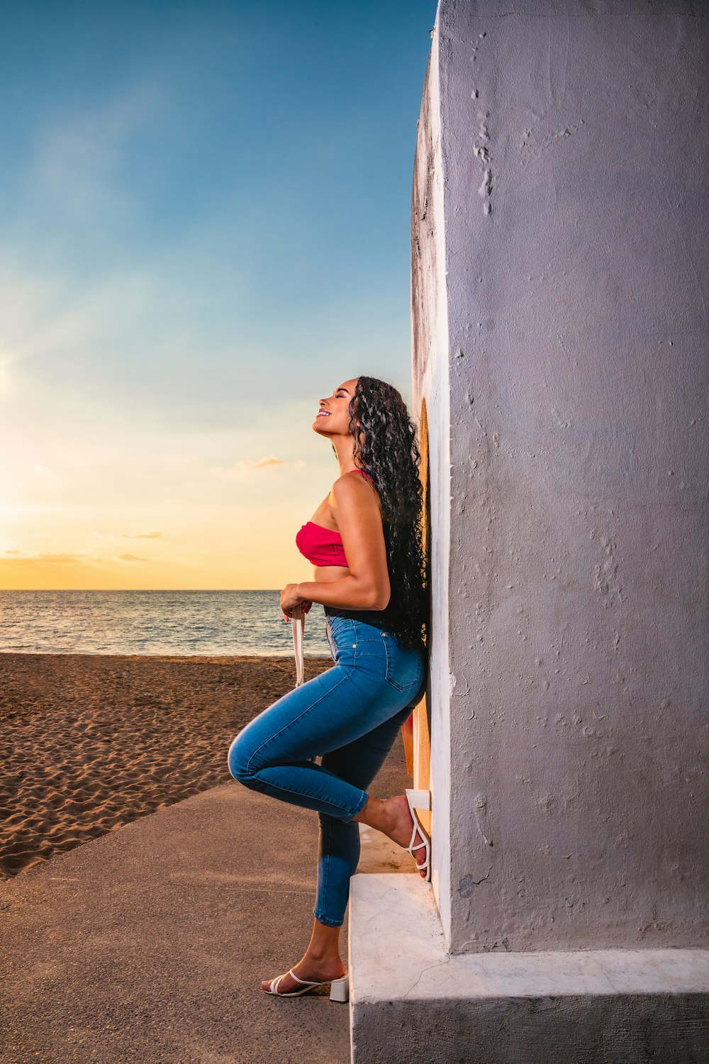 a woman leaning against a wall on the beach