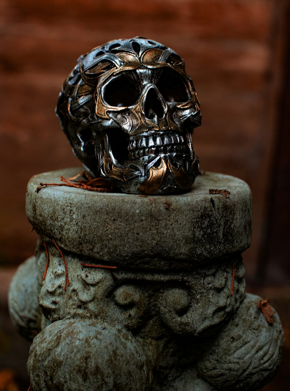 Eine Totenkopfstatue sitzt auf einem Zementpflanzgefäß