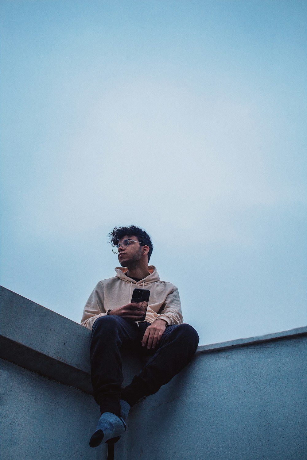 a man sitting on a ledge with a cell phone