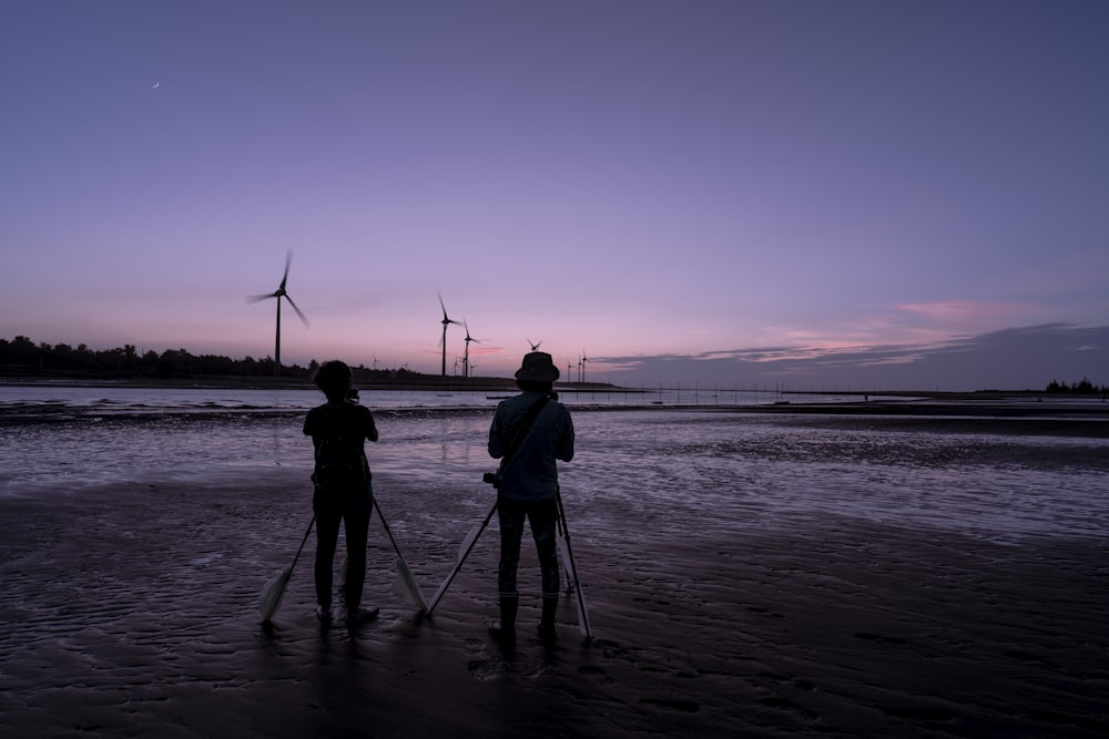 a couple of people standing on top of a beach