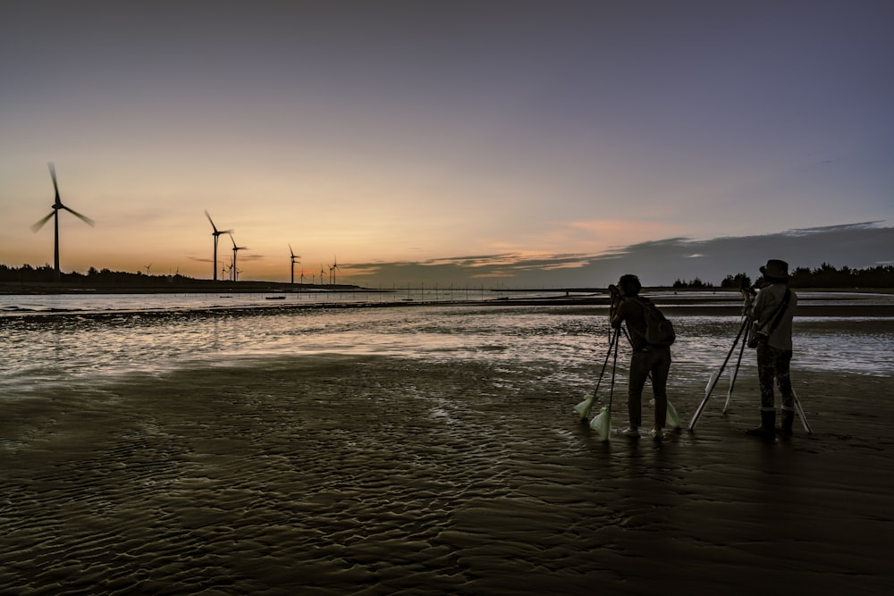 a couple of people standing on top of a beach