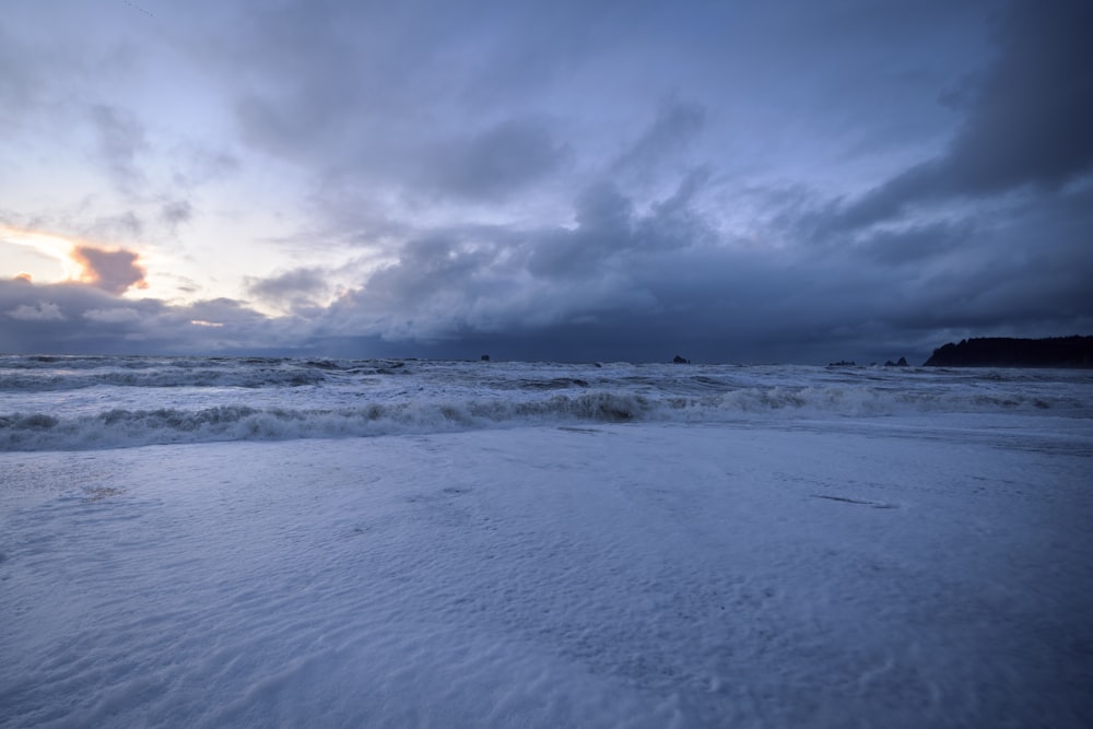 a beach covered in snow under a cloudy sky