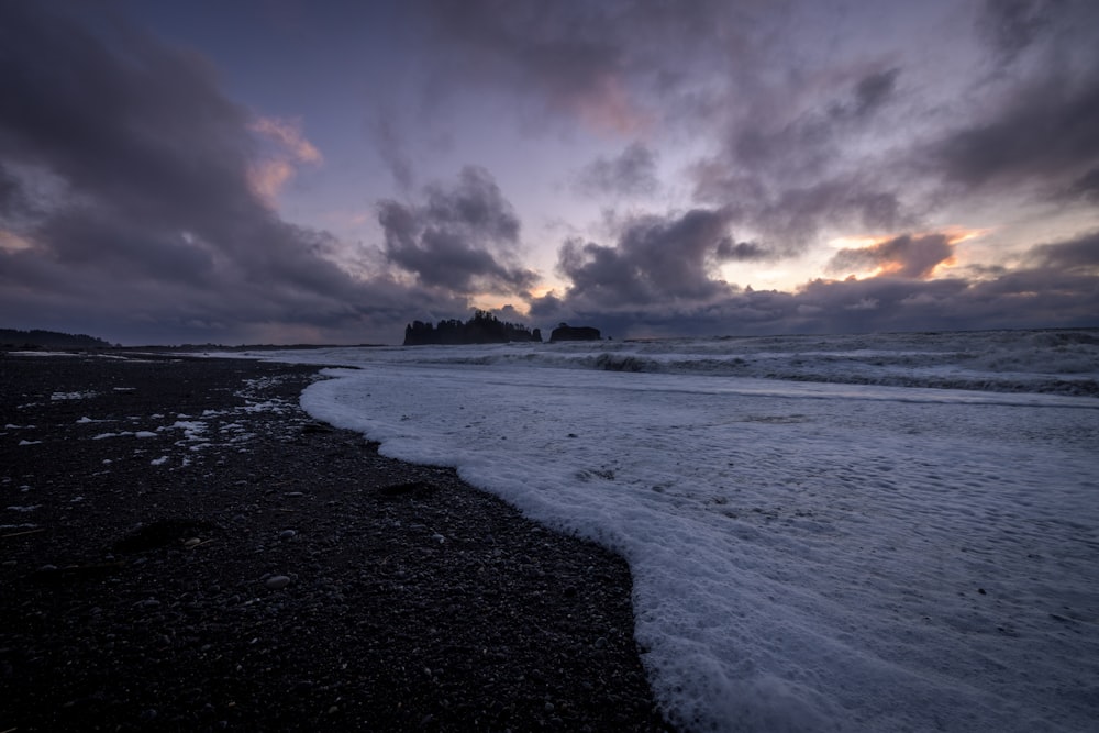 a beach covered in snow under a cloudy sky