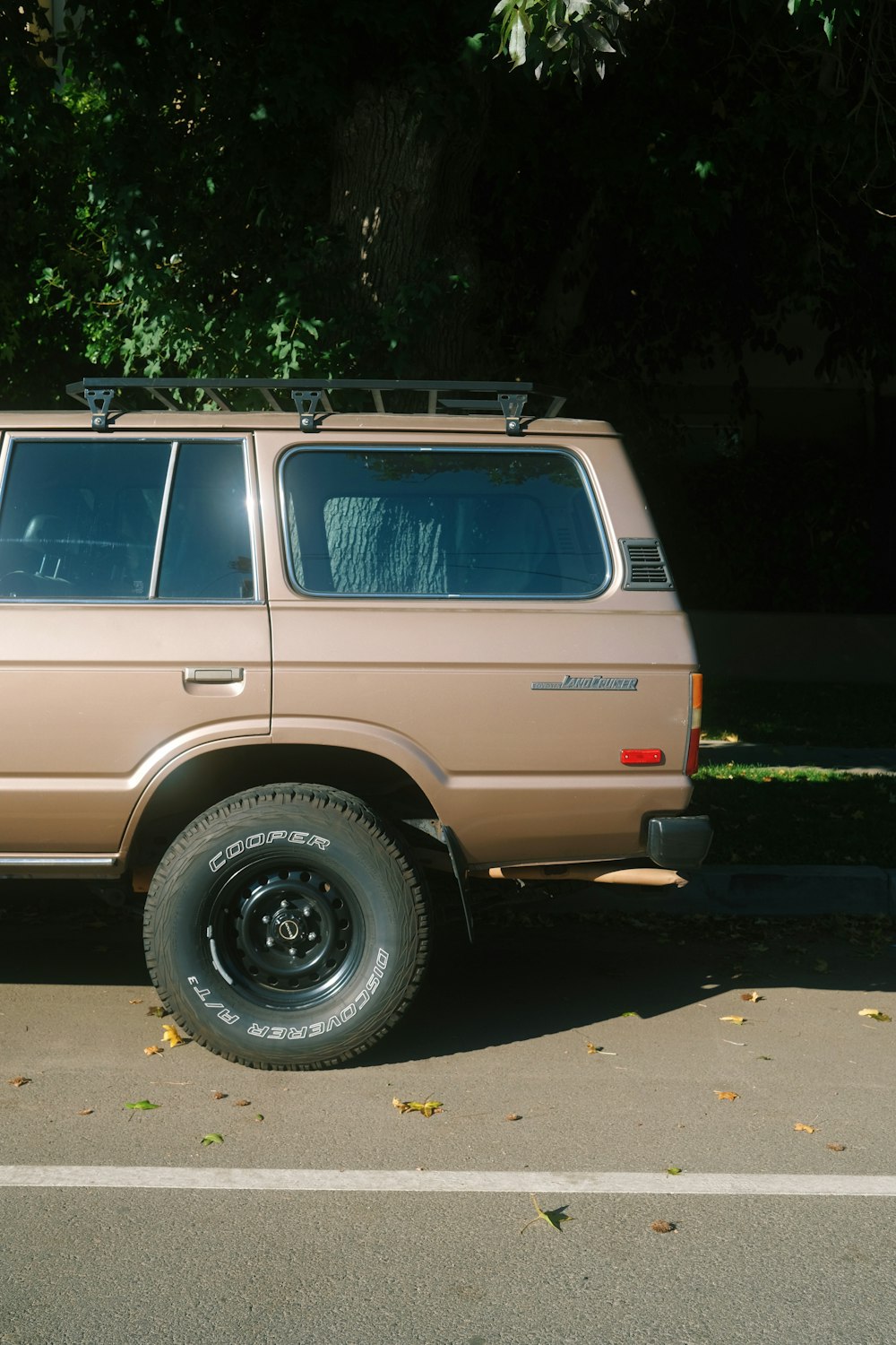 a tan suv parked on the side of the road