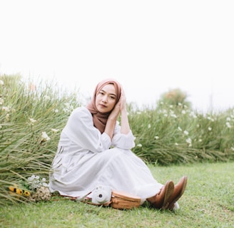 a woman in a white dress sitting in a field