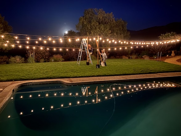 Technician installing electrical wiring near a swimming pool at sunset.