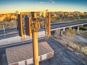 A mobile 5G tower standing tall on an empty plot of land at sunrise.