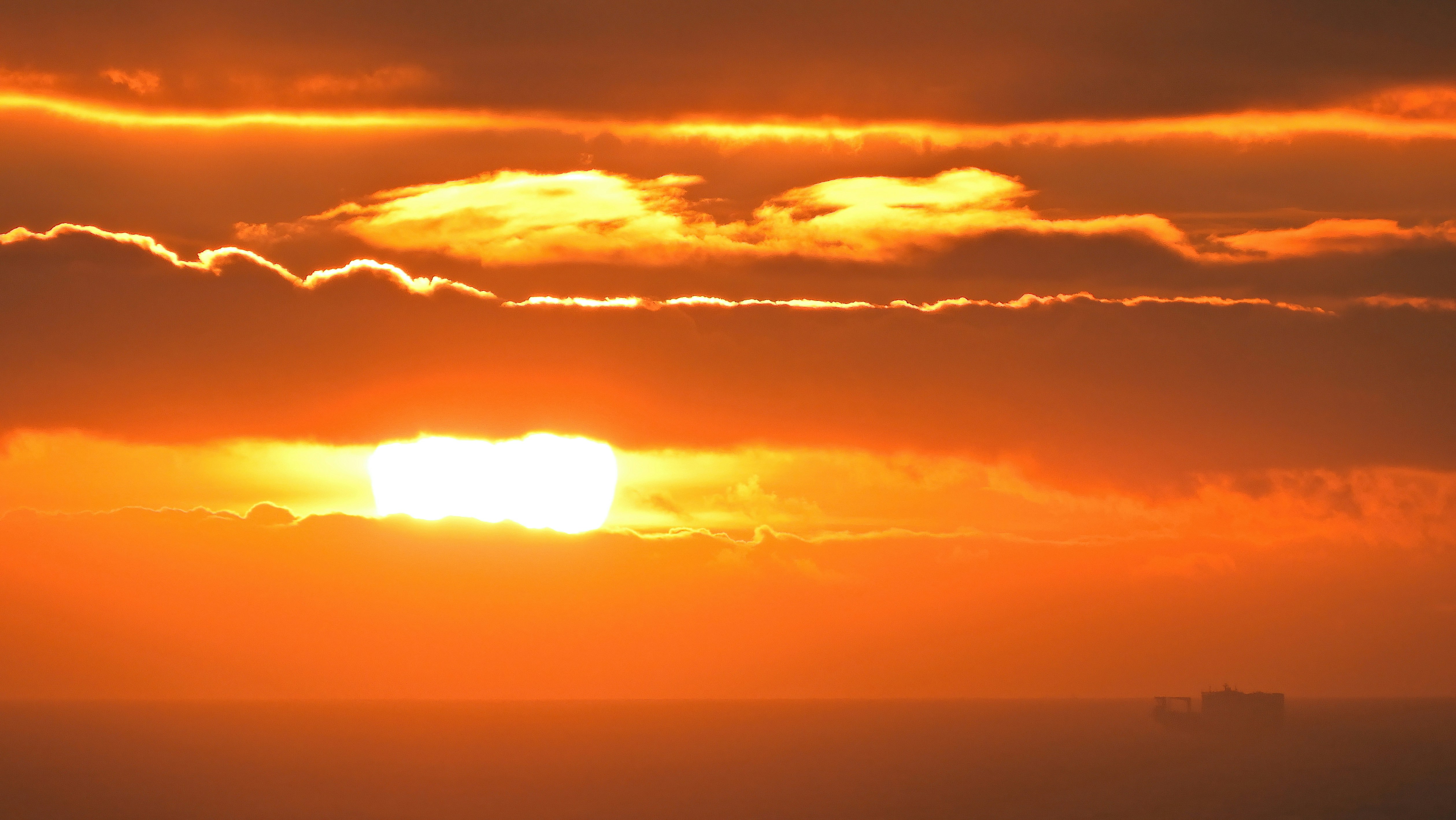 the-sun-is-setting-over-the-horizon-of-a-body-of-water-photo-free