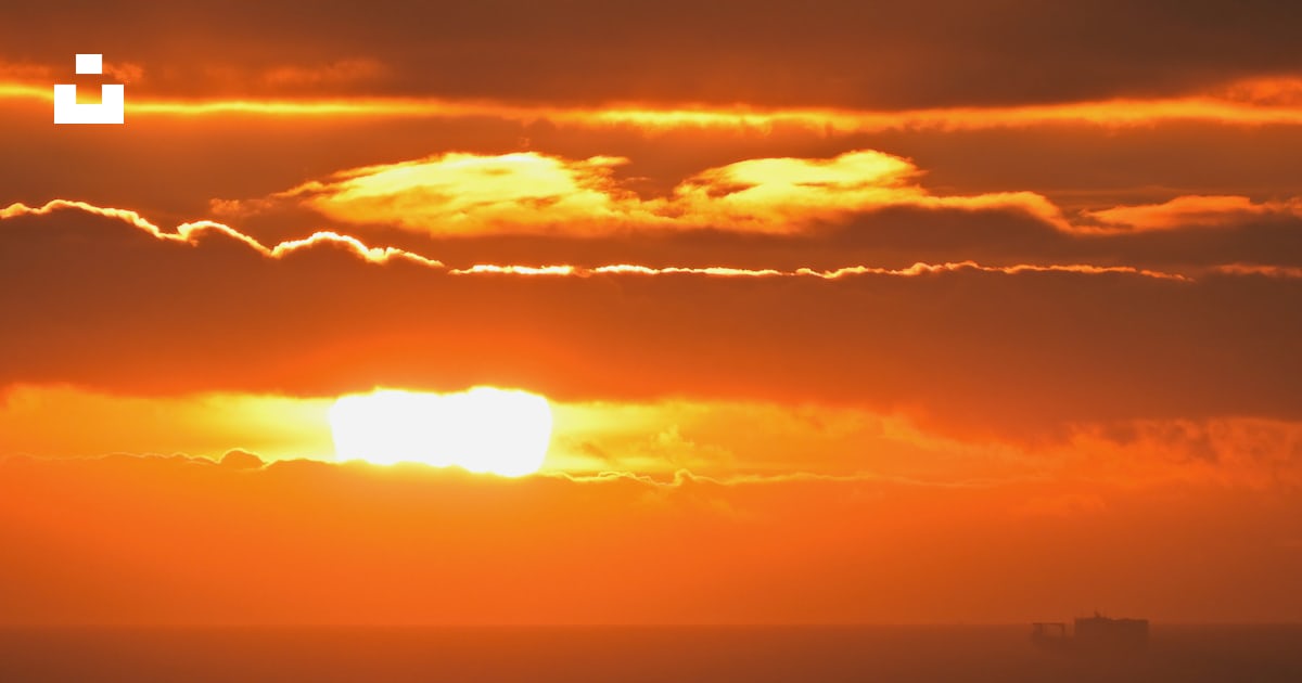 The Sun Is Setting Over The Horizon Of A Body Of Water Photo Free the-sun-is-setting-over-the-horizon-of-a-body-of-water-photo-free