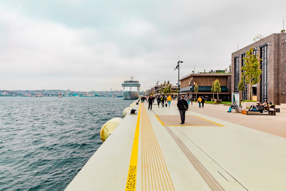 people walking on a pier next to a body of water