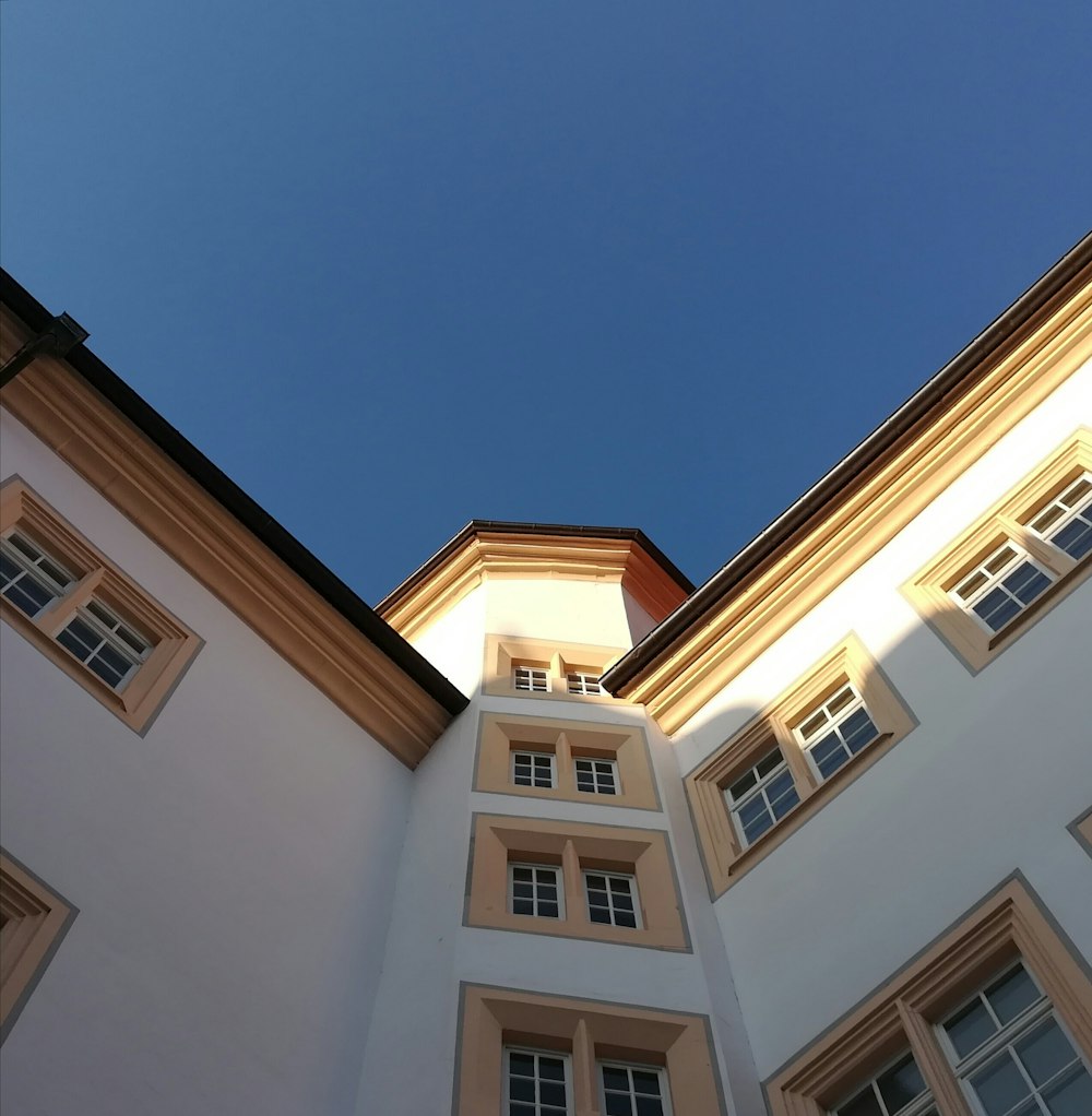 a tall white building with windows and a sky background