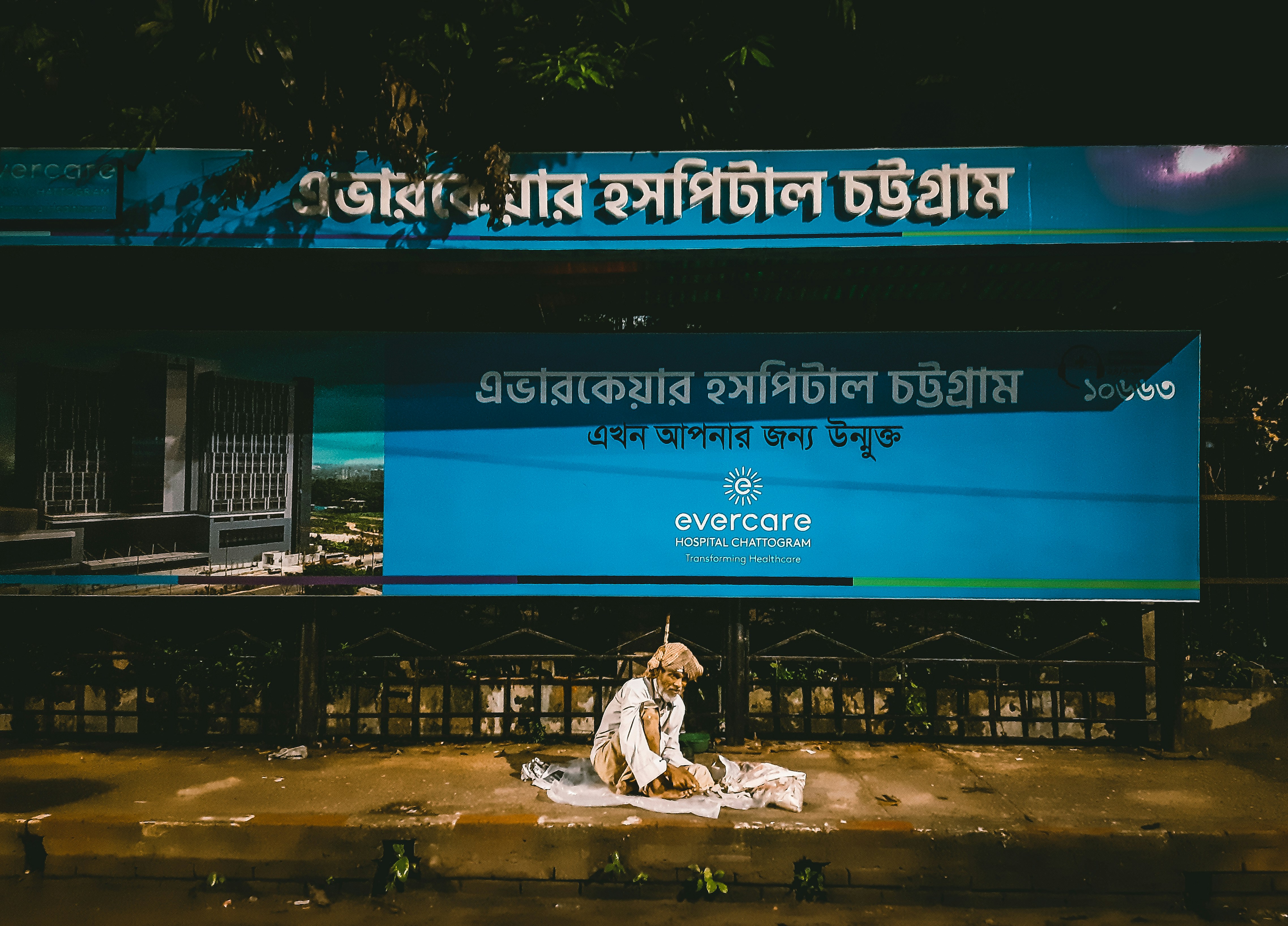 a man sitting on the ground in front of a sign