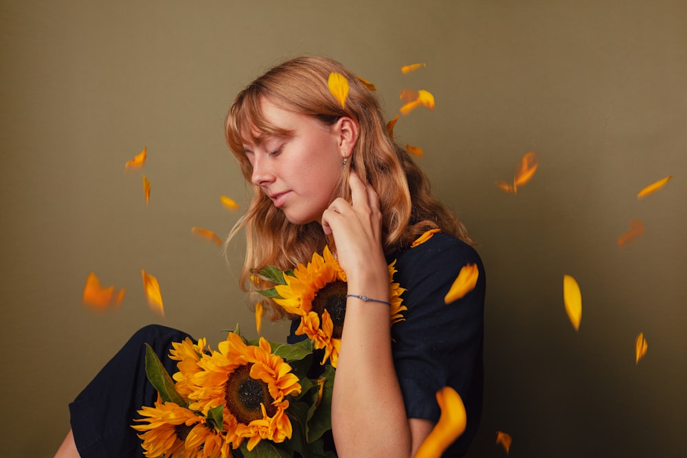 Una mujer sosteniendo un ramo de girasoles frente a su cara