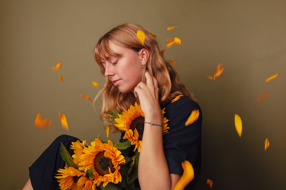 a woman holding a bouquet of sunflowers in front of her face