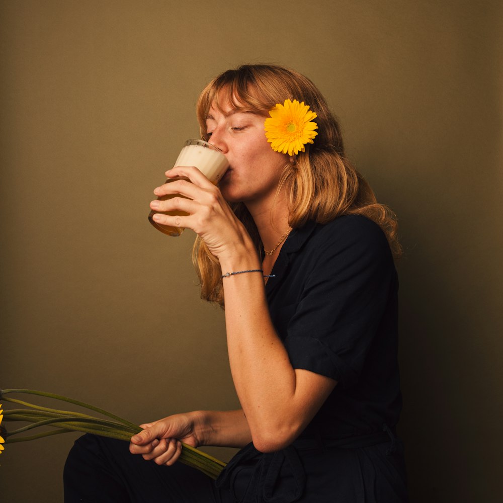 a woman drinking a cup of coffee with a flower in her hair