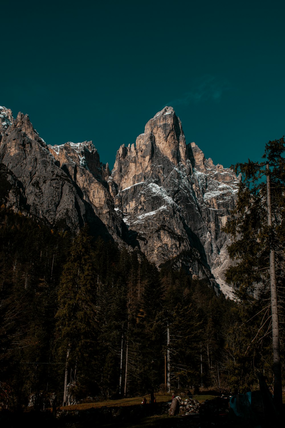 a mountain range with trees and a tent in the foreground