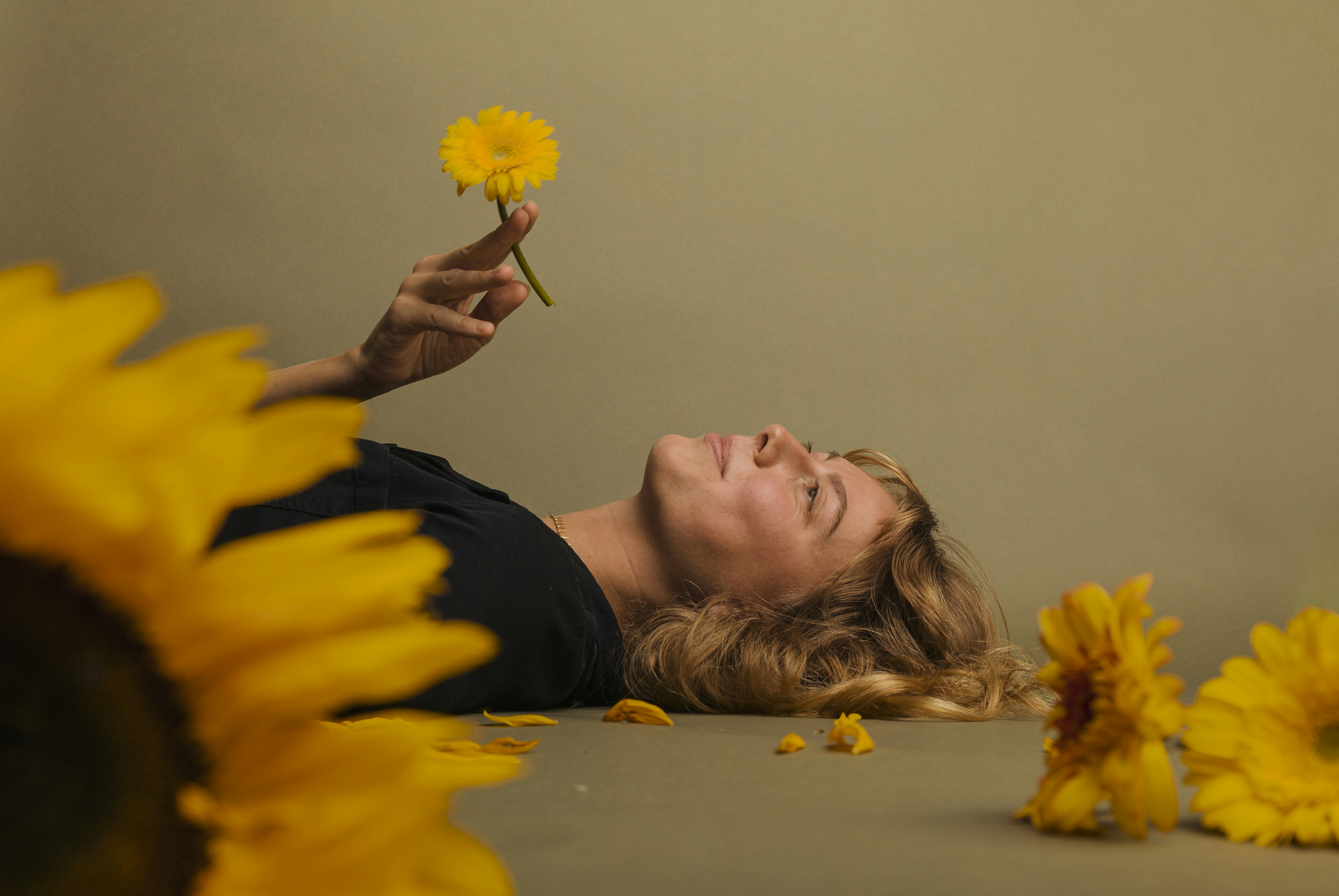 a woman laying on the ground with a flower in her hand