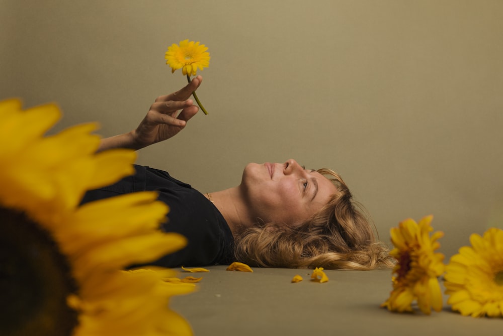 a woman laying on the ground with a flower in her hand