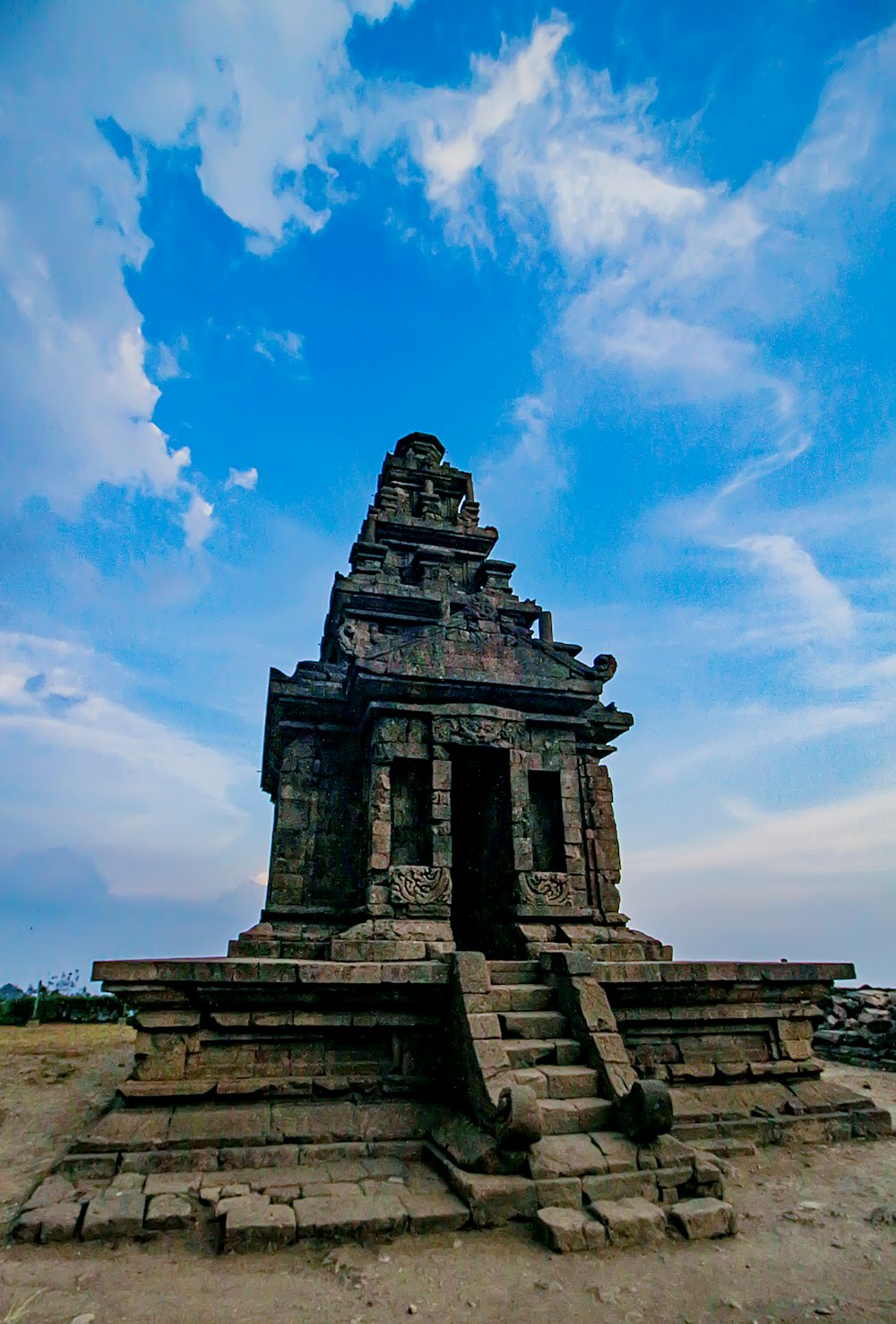 a stone structure in the middle of a dirt field