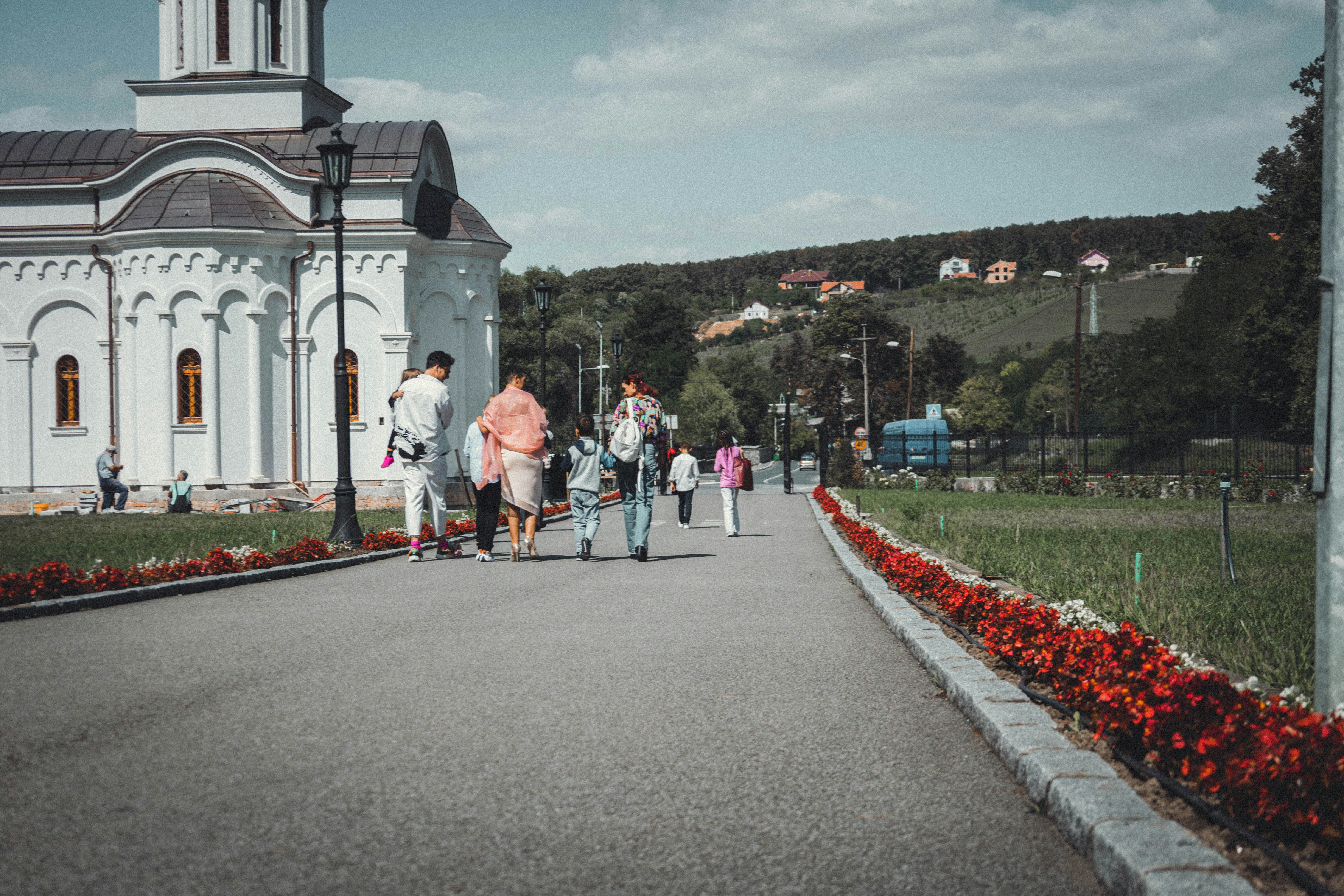 a group of people walking down a road near a church