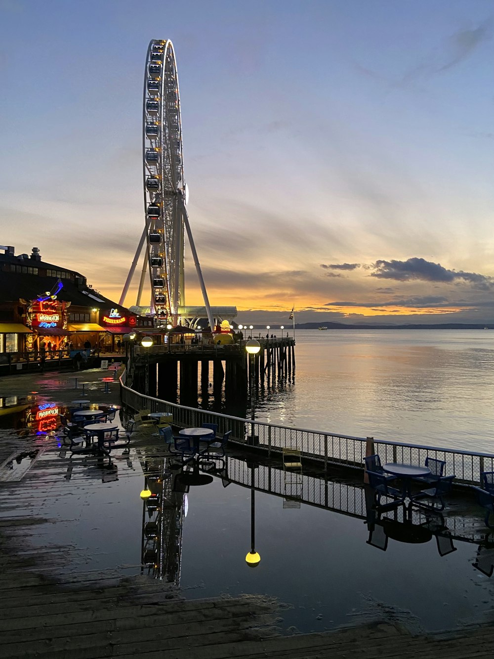 a ferris wheel sitting on top of a pier next to the ocean