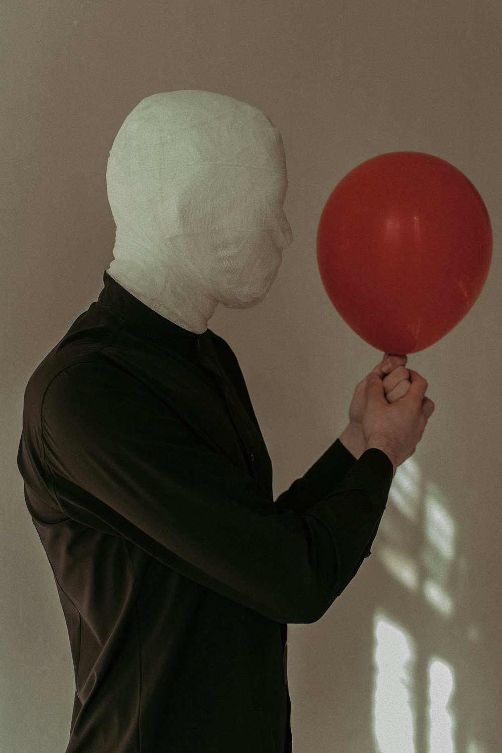 uma pessoa em uma máscara branca segurando um balão vermelho