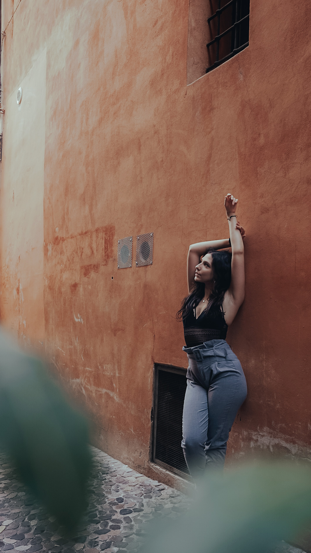 a woman leaning against a wall with her hand on her head