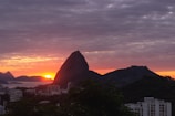 Sunset over iconic Sugarloaf Mountain with city lights.