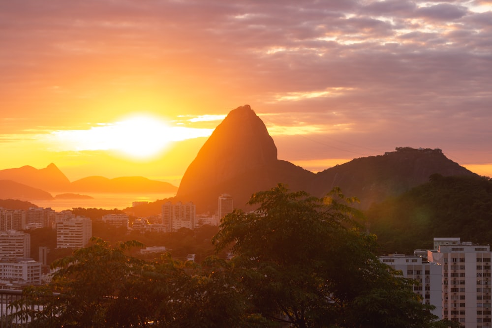 the sun is setting over a city with mountains in the background