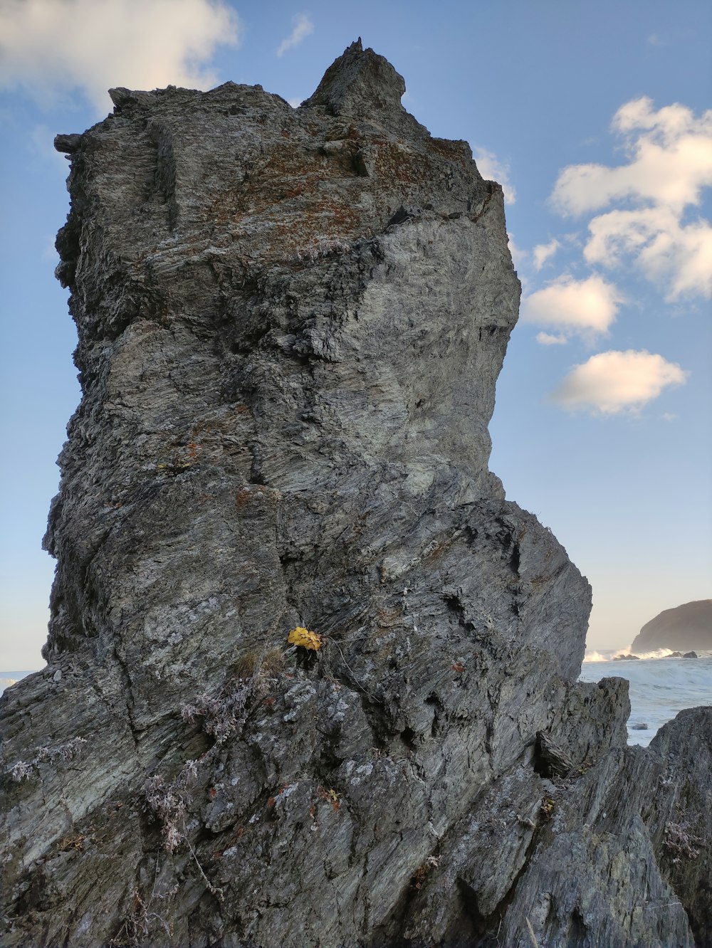 a rock outcropping on a beach with a body of water in the