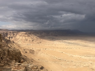 A vast desert landscape under a dramatic cloudy sky.